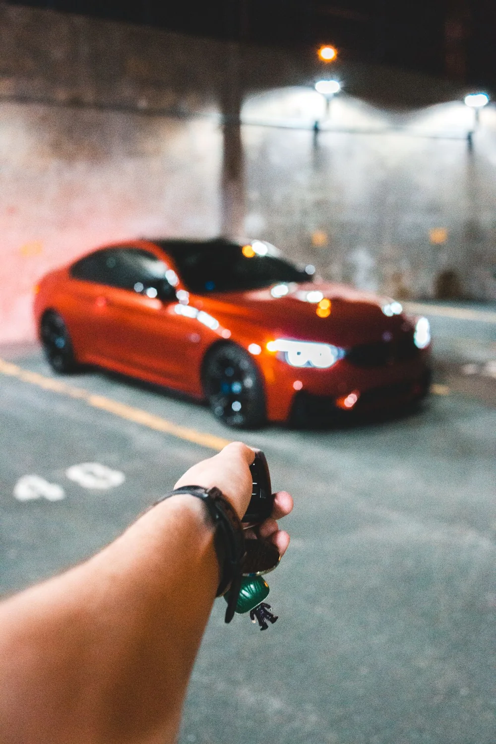 Car key fob held beside a vehicle in a parking garage